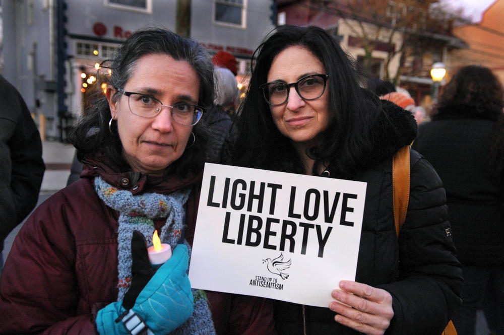 Two women  bundled up for cold weather with protest sign that says Light Love Liberty