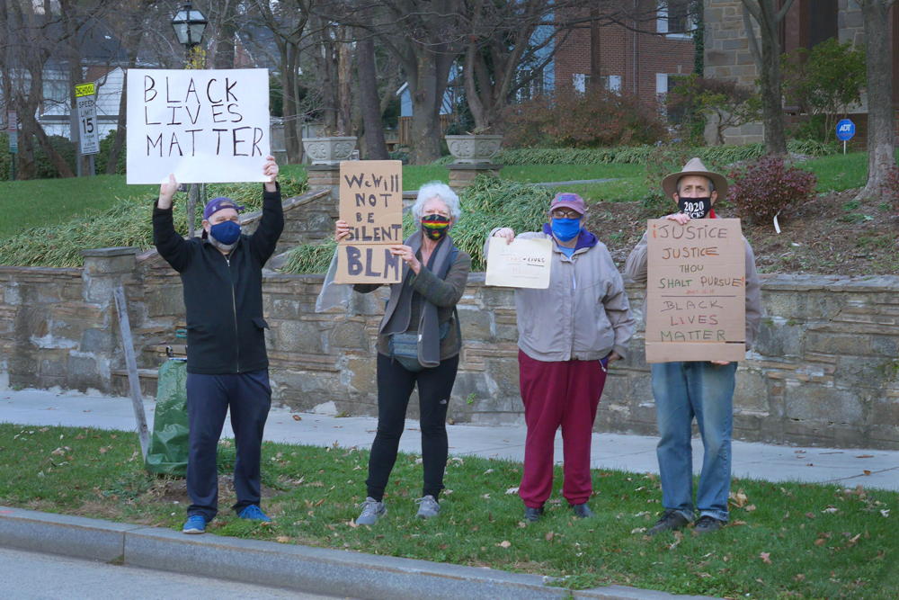 4 people on sidewalk holding Black lives matter protest signs